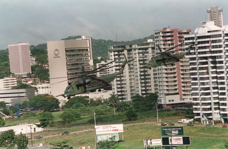 View of two helicopters flying low amid high rise buildings, seemingly taken from another helicopter.