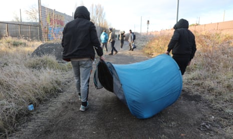 Migrants carrying their belongings are moved on from their makeshift camp near Calais.