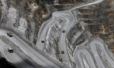 Shot from above of vehicles driving up a grey road with multiple hairpin bends
