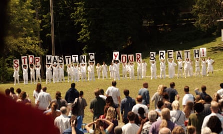 Cult members in white holding signs that read 'stop wasting your breath'