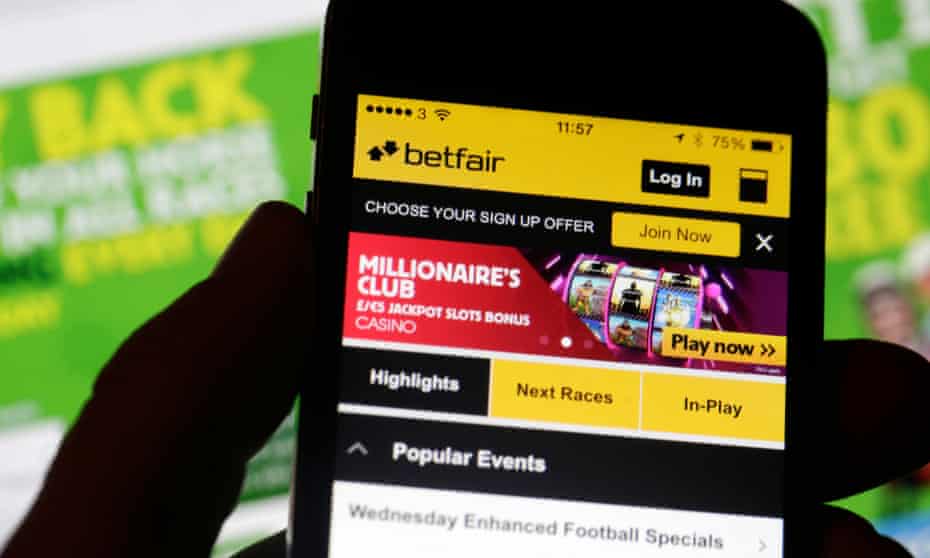 A smartphone with the Betfair Group Plc app is held in front of the Paddy Power Plc website in this arranged photograph