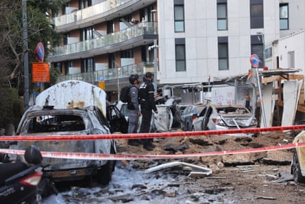 Security teams stand next to burned out cars and wreckage