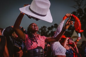 A woman raises a hat as a group line-dances at night