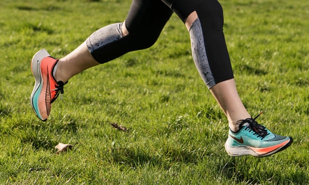 A person running on grass, photographed from the knees down