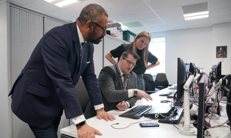James Cleverly (left), the home secretary, with the minister for victims and safeguarding, Laura Farris (right), speak to a Met police officer (seated) at Hammersmith police station in west London