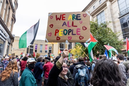 Protesters holding flags and placards – one says We Are all People