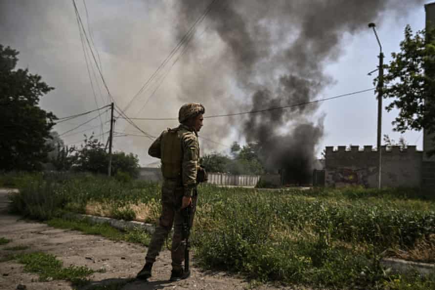 A Ukrainian serviceman stands in front of a burning vehicle during an artillery duel between Ukrainian and Russian troops in the city of Lysychansk, eastern Ukrainian region of Donbas.