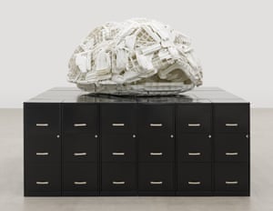 Brian Jungen, Tombstone. The sculpture by the Canadian First Nations artist is made of white, plastic Rubbermaid step stools reassembled into the shape of a turtle's shell which rests atop a platform of 32 black, metal filing cabinets. The work references Turtle Island, a name for North America used by many Indigenous communities, while the filing cabinets allude to the colonial bureaucracy that American and Canadian governments have inflicted upon Indigenous peoples through broken treaties, violent land grabs and false promises of sovereignty.