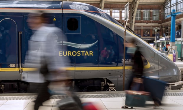 Travellers walk past a Eurostar train at Lille train station.