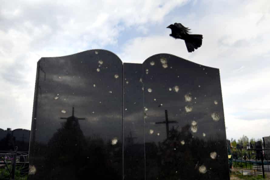 Birds fly past a tombstone damaged by the war in Bucha.