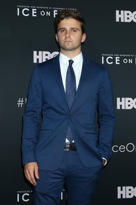 man stands in suit with hand in pocket on red carpet, with ‘hbo’ and ‘ice on fire’ logos behind him