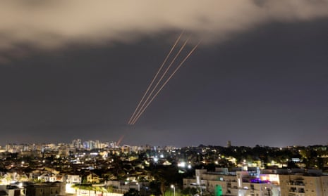 An anti-missile system fires into the sky over buildings at night