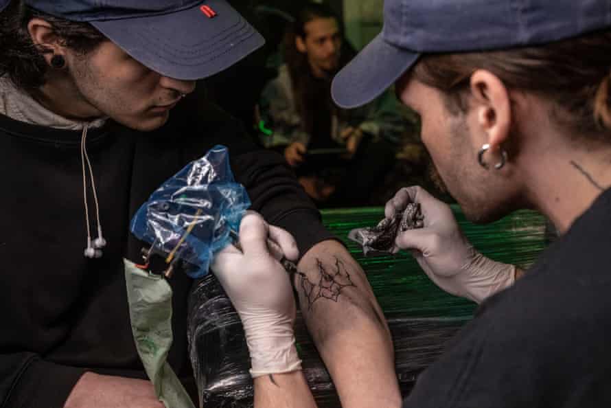 A stylized Ukrainian coat of arms tattooed on a man's left arm, during a tattoo marathon