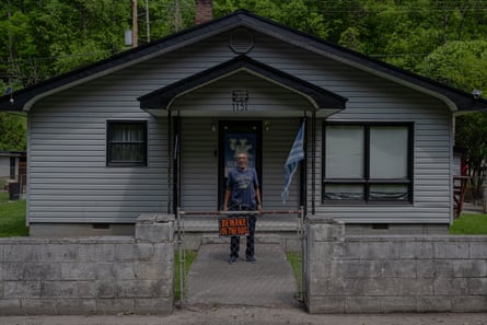 man standing outside of home behind fence and stone wall