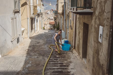 A woman fills containers with water from a pipe