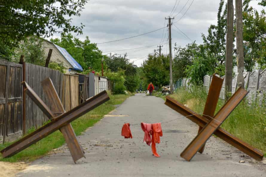 A woman walks on a street blocked by “Czech hedgehog” anti-tank devices in Novoselivka village, Chernihiv.