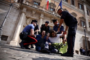 A female protester sitting on the ground cries out as officers lift her and a male colleague to their feet