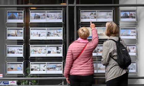 People look over sales options at an estate agent's window