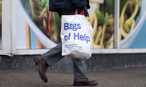 A man carrying a Tesco bag for life along a street