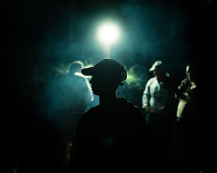 A man in a cap silhouetted with a crowd in the background
