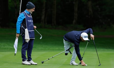 Arce, a golfer with one leg from Santander in Spain, balances his putter and crutches as he bends down to mark his ball on the 15th green