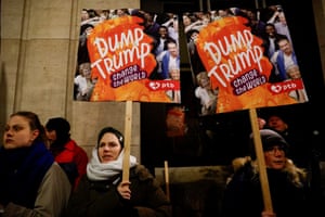 people hold signs outside that read ‘Dump Trump change the world'