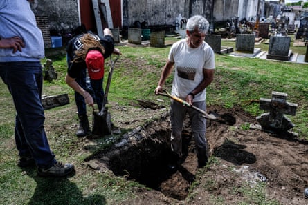a man stand with a shovel in a half-excavated grave