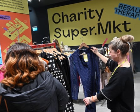 Two people look through the clothing rails at a charity shop
