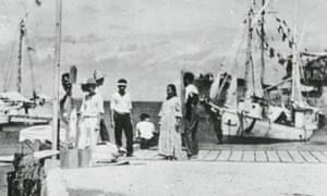 The woman said to resemble pilot Amelia Earhart is seen sitting on the dock in the centre of the picture.