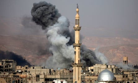 Smoke rises behind a minaret in Arbin, Syria