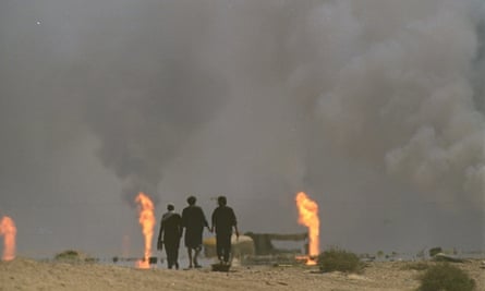 Three Kuwaiti refugees head toward Kuwait City from the Iraqi border in March 1991, as oilwells burn.