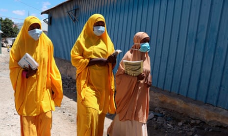 Students walk in a Mogadishu neighbourhood wearing face masks, Somalia