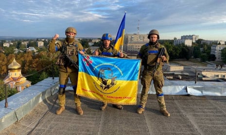 Ukrainian soldiers hold a flag at a rooftop in Kupiansk, Ukraine in this picture obtained from social media.