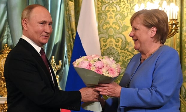 Vladimir Putin welcomes Angela Merkel with a bouquet of flowers at the Kremlin