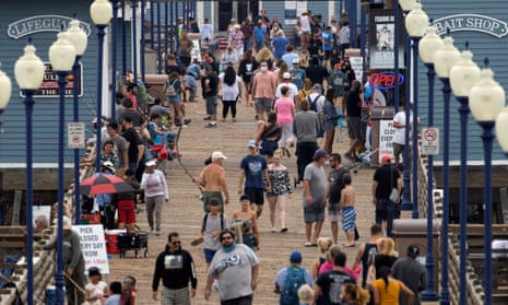 Few people wear masks as they walk on a pier in Oceanside, California, on Monday.