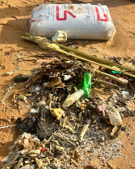 A sack and plastic debris in a pile on a beach