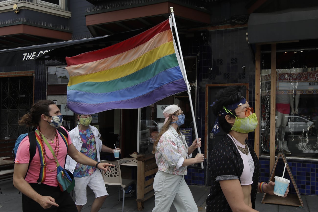 Zina Goodall carries a rainbow flag through San Francisco’s Castro District. Several new studies point to the vast health disparities LGBTQ+ people face amid the pandemic.