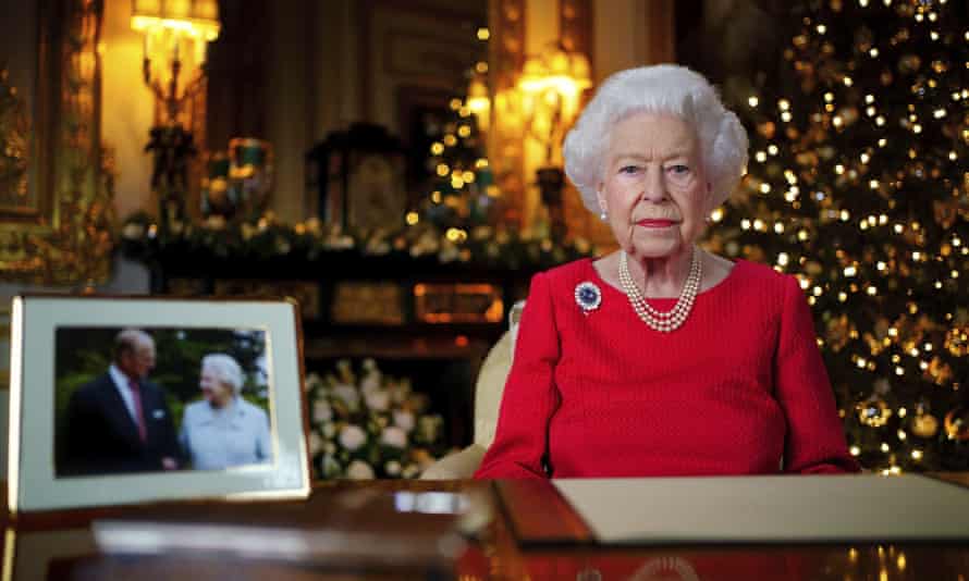 Queen Elizabeth II recording her annual Christmas broadcast at Windsor Castle in 2021, beside a picture of herself and Prince Philip taken in 2007 to mark their diamond wedding anniversary.