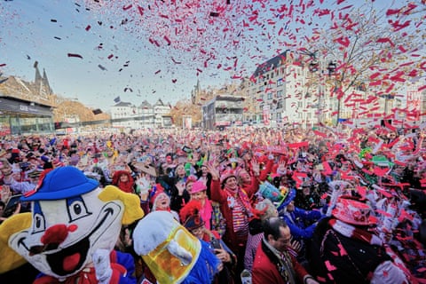 A crowd of costumed people smiling as confetti rains down on them.