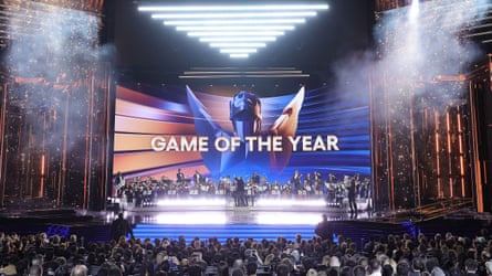 A crowd viewing a stage featuring an orchestra and a backdrop with the text ‘Game of the Year’.