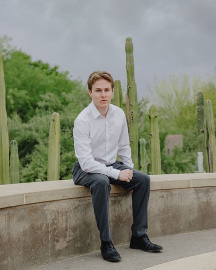 a young man wearing a white shirt and gray slacks, posing for a photo