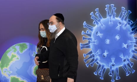 A couple walk past a coronavirus graphic in a vaccination centre in Jerusalem, Israel.