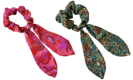A pink scarf scrunchie next to a dark green patterned one on a white background