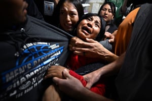 Young girls in distress hold on to their relative as he is taken away