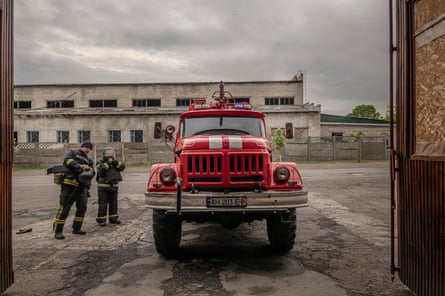 Firefighters put on their equipment next to a fire engine