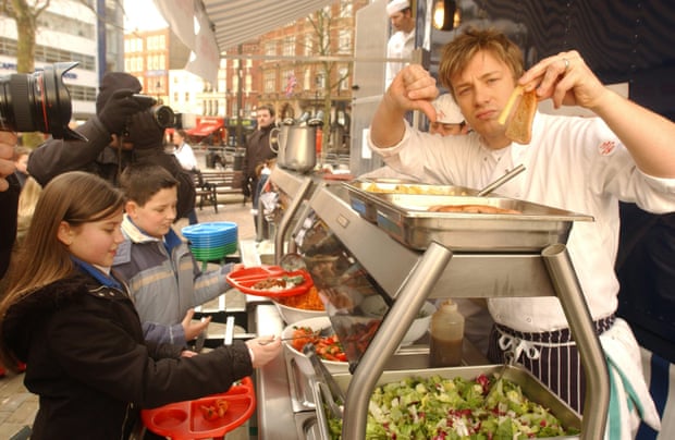 Serving up culinary opposition … Oliver gives the thumbs down to chips and fatty food as he serves up a healthy lunch at Ealdham primary school in London in 2005.