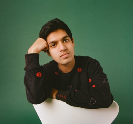 Ziad Ahmed sitting backwards on a white chair, photographed against a green background