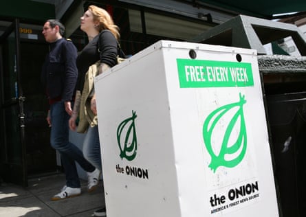 people walk past white box with the Onion’s green onion logo