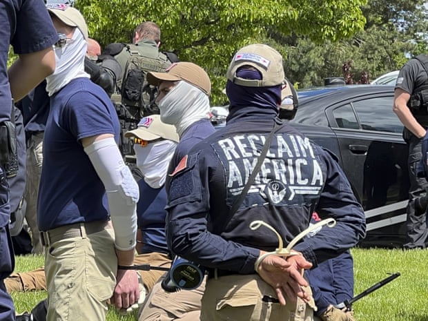 Men in handcuffs kneeling on the grass