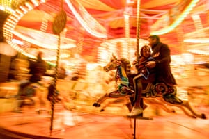 A father rides a merry-go-round with his son